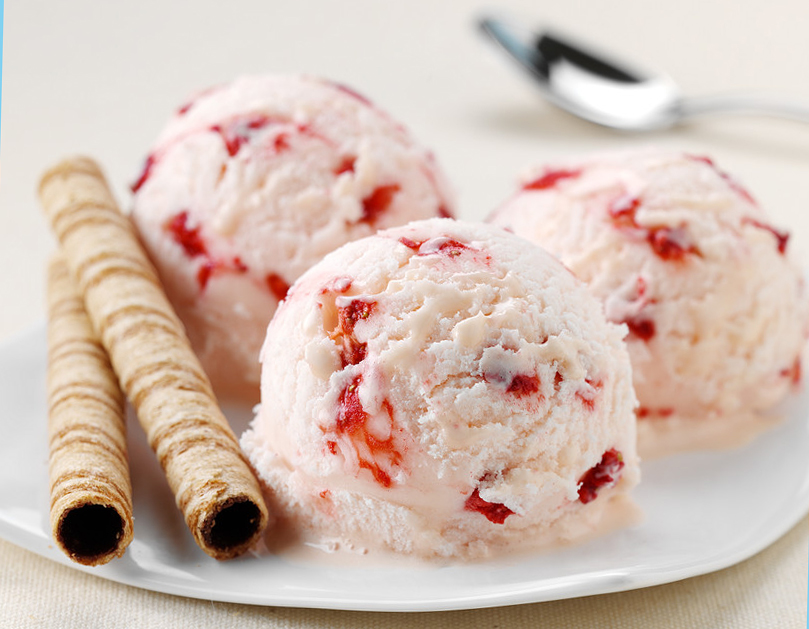 pink strawberry ice cream with red strawberries on a plate with wafer straws