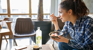 Lady eats yoghurt over a low table