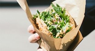 Hand holding a vegan burger with salad